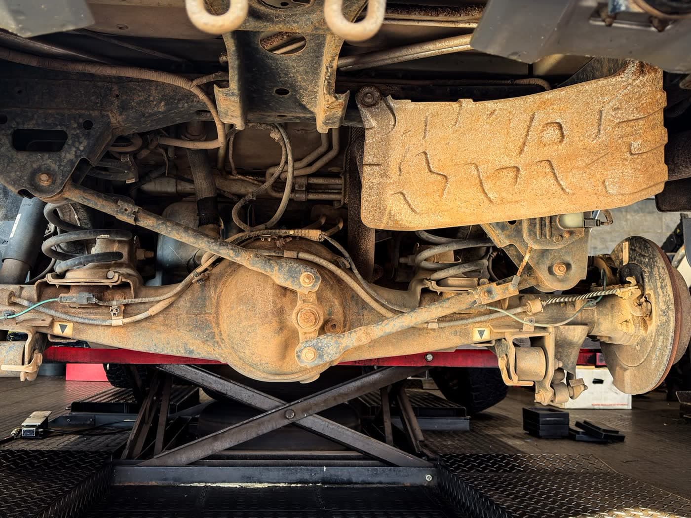 Vehicle suspension components seen from underneath during a repair